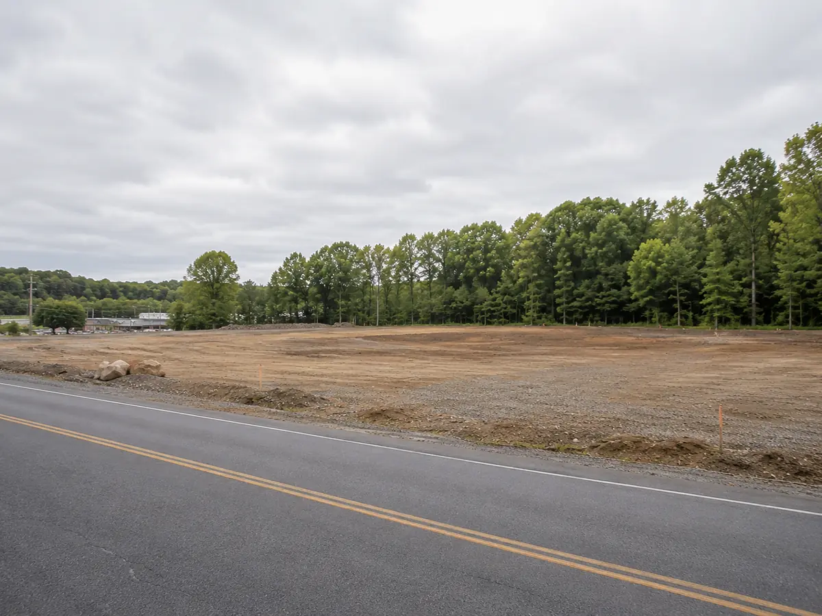 Cleared commercial development parcel with road frontage and a wooded tree line